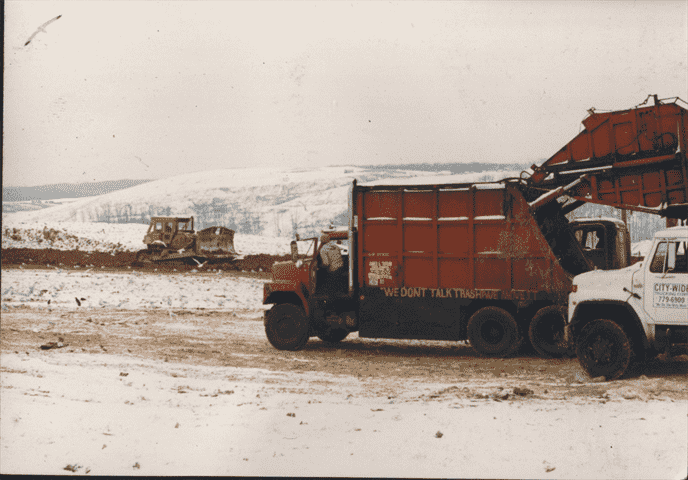 Rear load trucks and a landfill in a snow storm